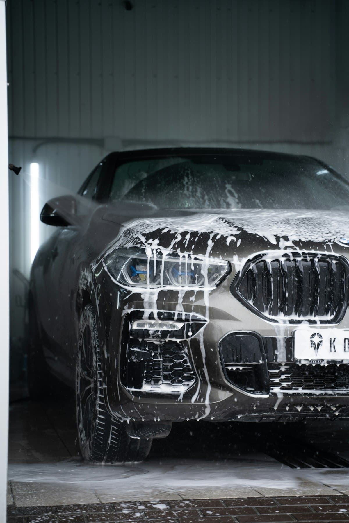 Dark SUV covered in snow foam during a detailing wash